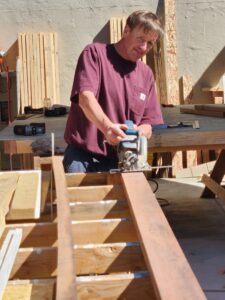 Tom using tools and looking at camera